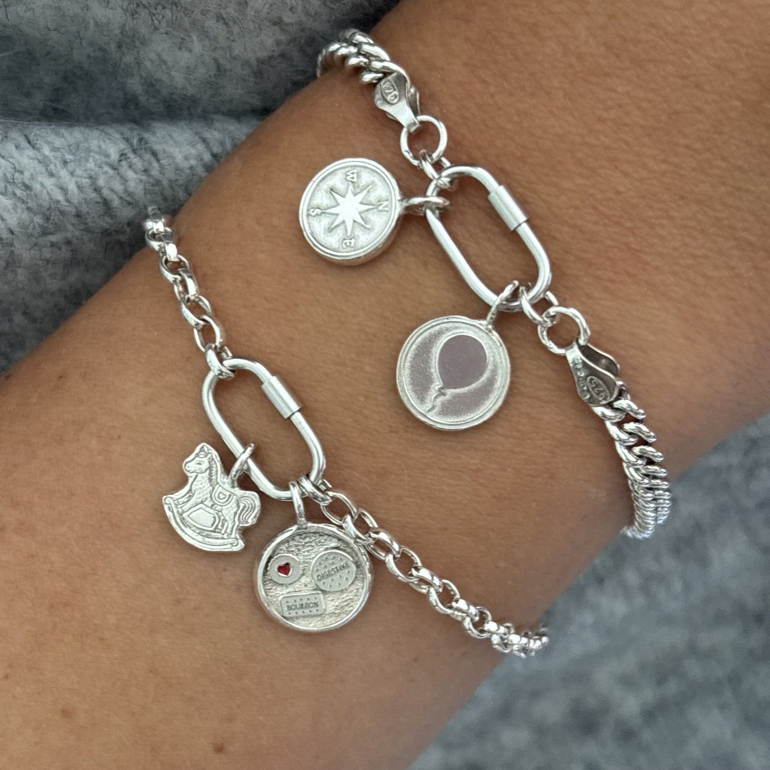 Two sterling silver braceletd with a compass charm, balloon charm, rocking horse charm and biscuit charm