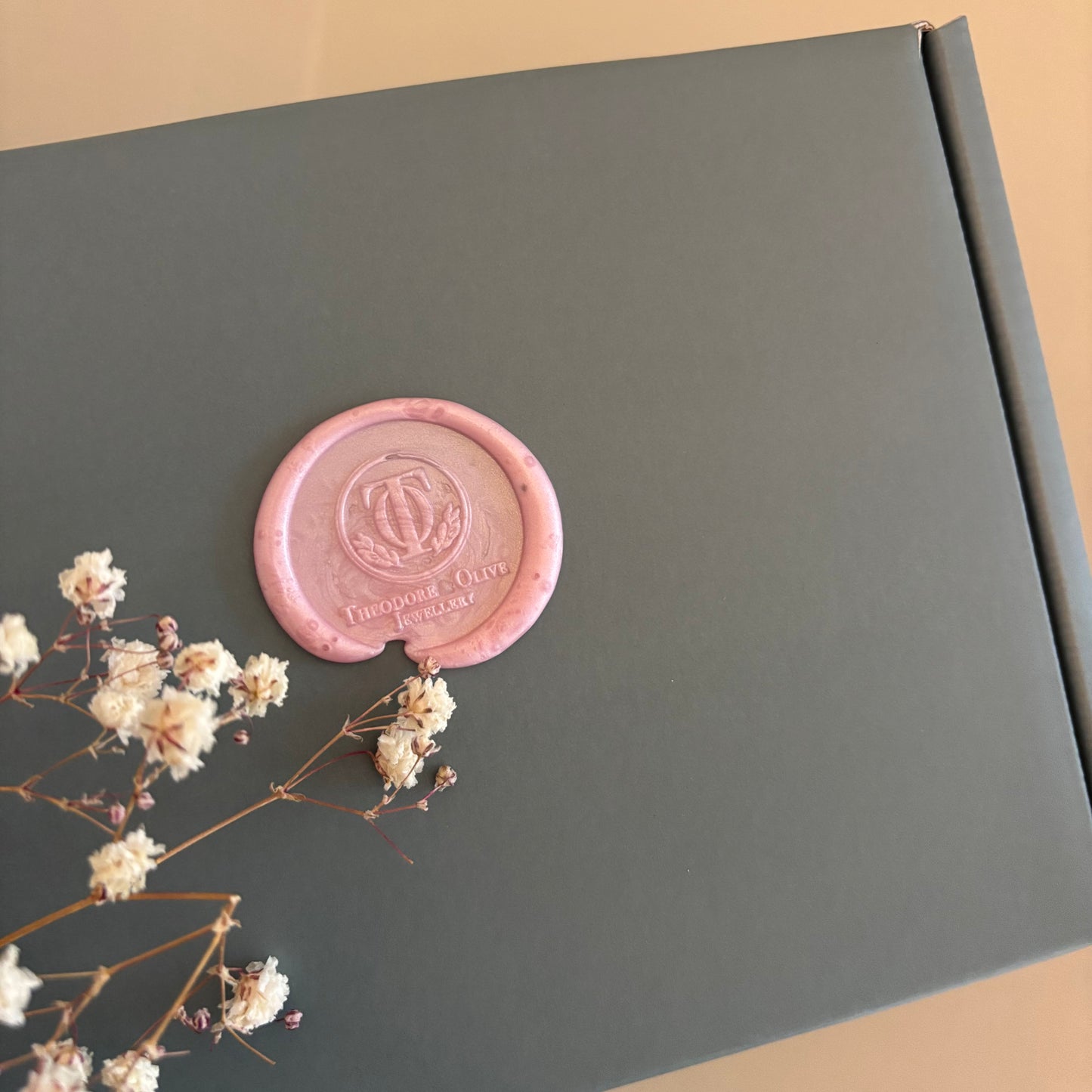 Sage green Theodore & Olive Jewellery gift box sealed with a blush pink wax seal, styled with dried flowers