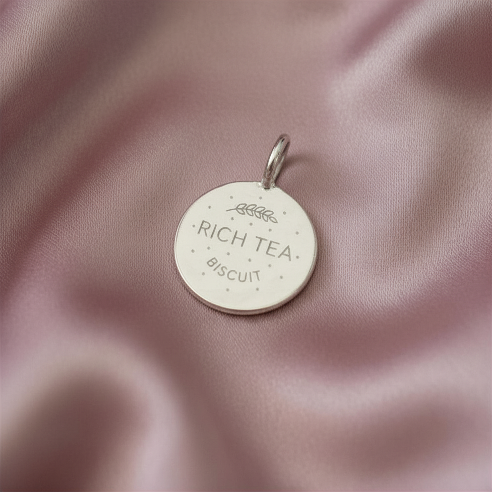 Silver digestive biscuit charm on dusky pink satin 