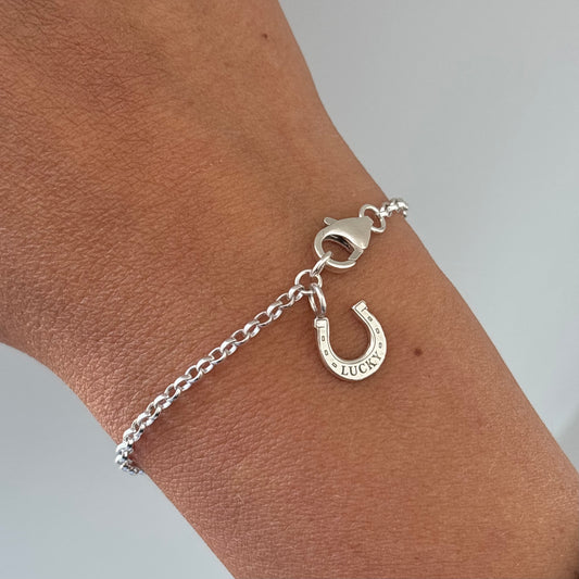 A lucky horse shoes charm bracelet in sterile g silver worn on a wrist 