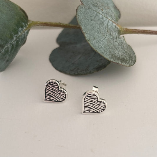 Sterling silver zebra print heart stud earrings with engraved line detail on a white background