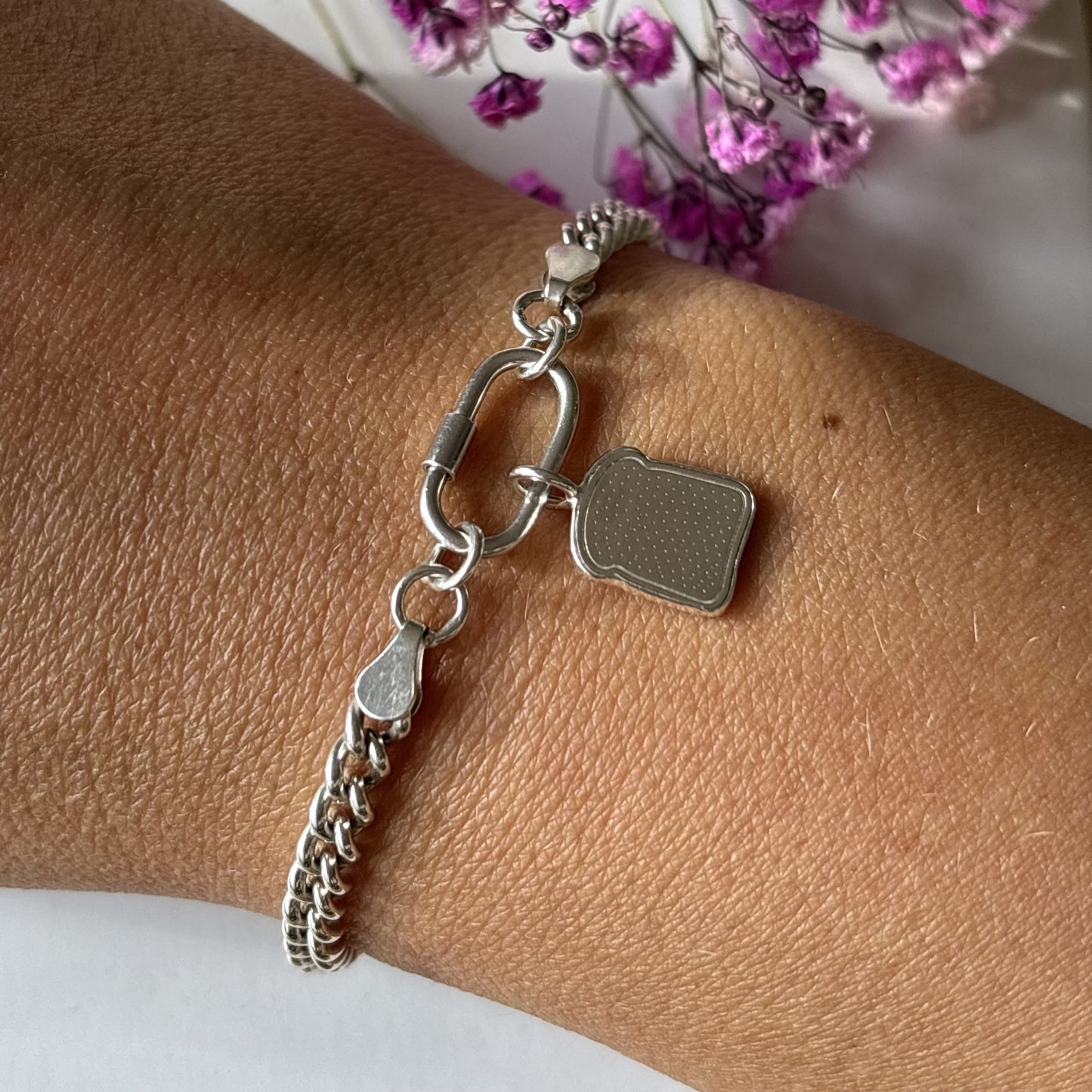 Handmade silver toast charm bracelet on wrist