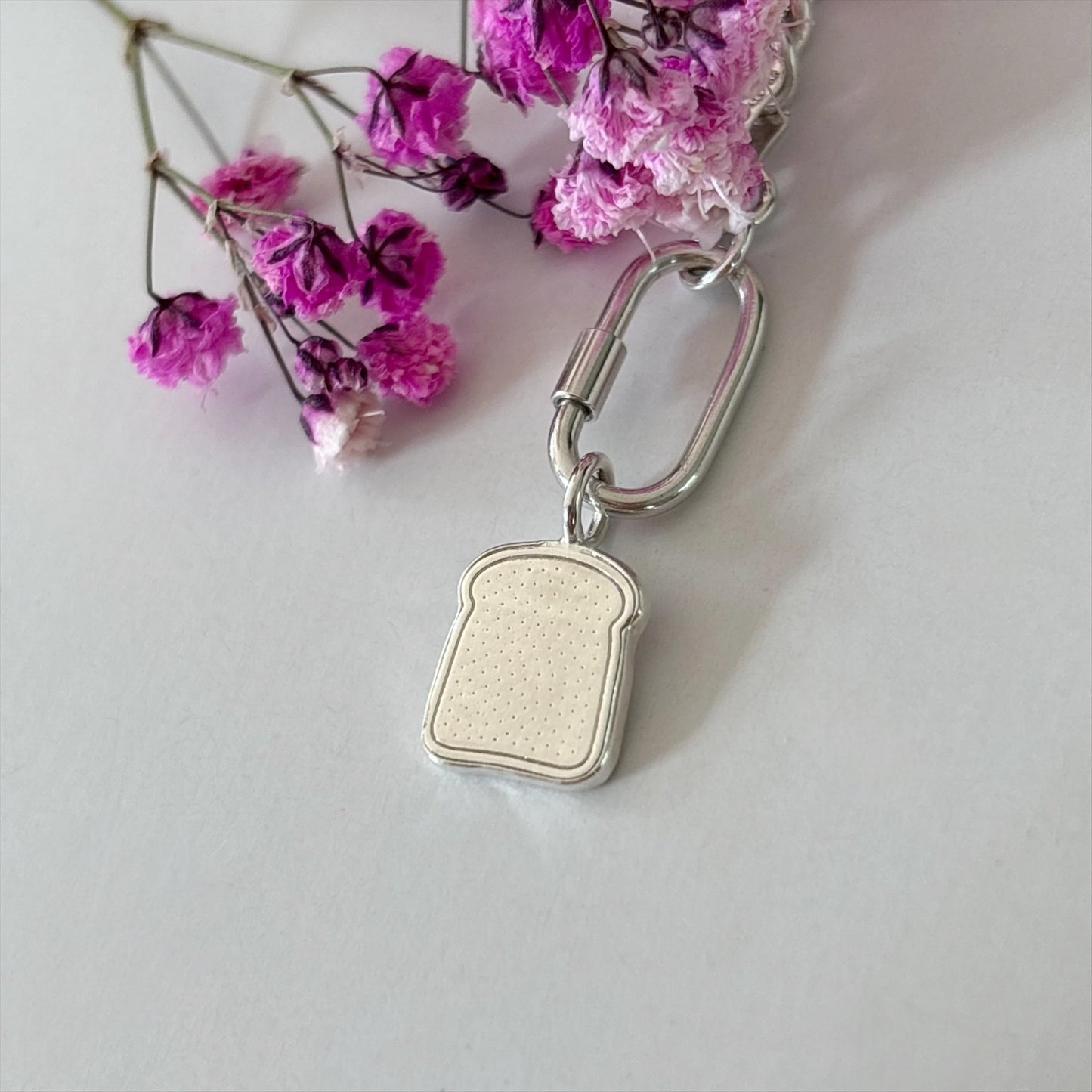 Silver slice of toast charm surrouded with flowers