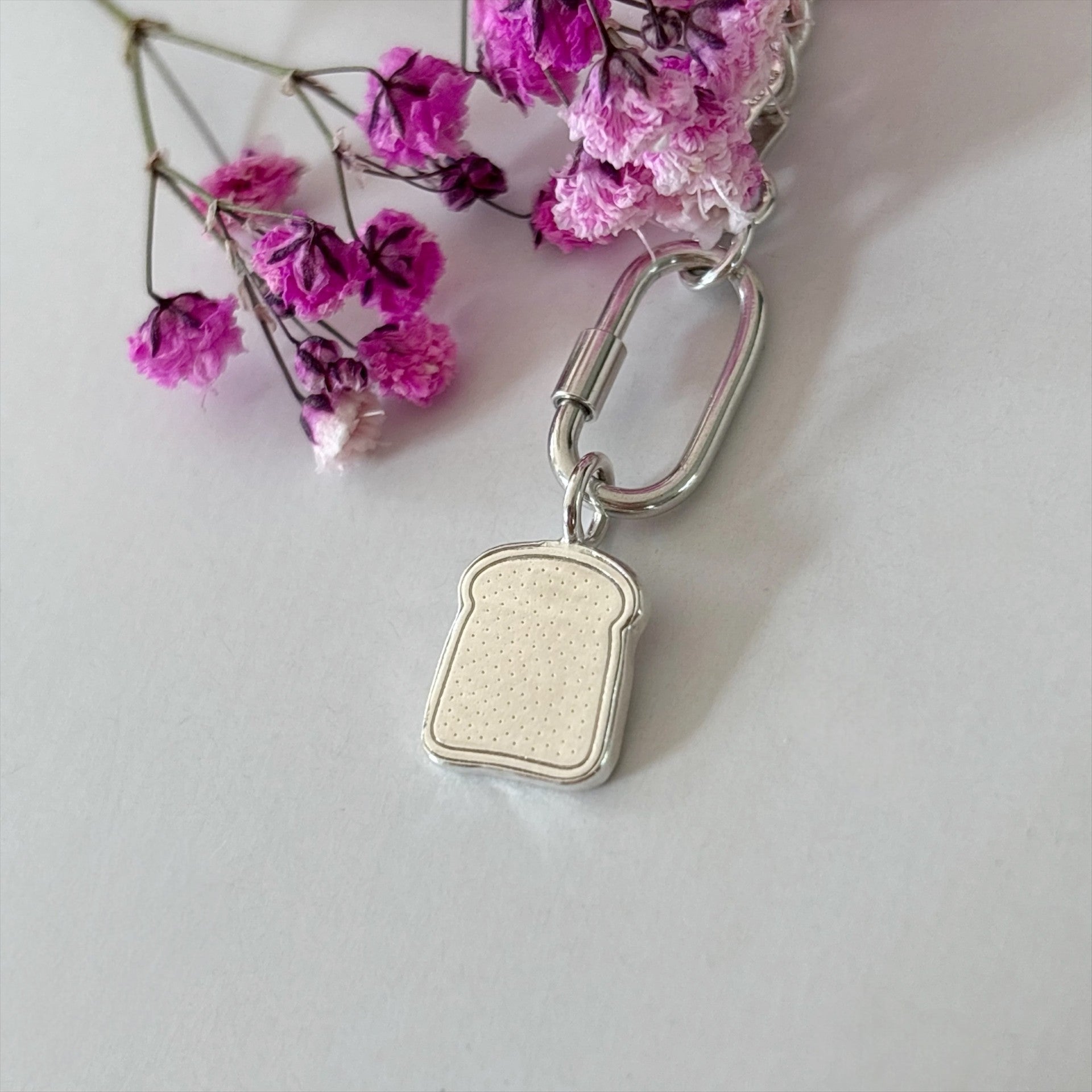 Silver slice of toast charm surrouded with flowers