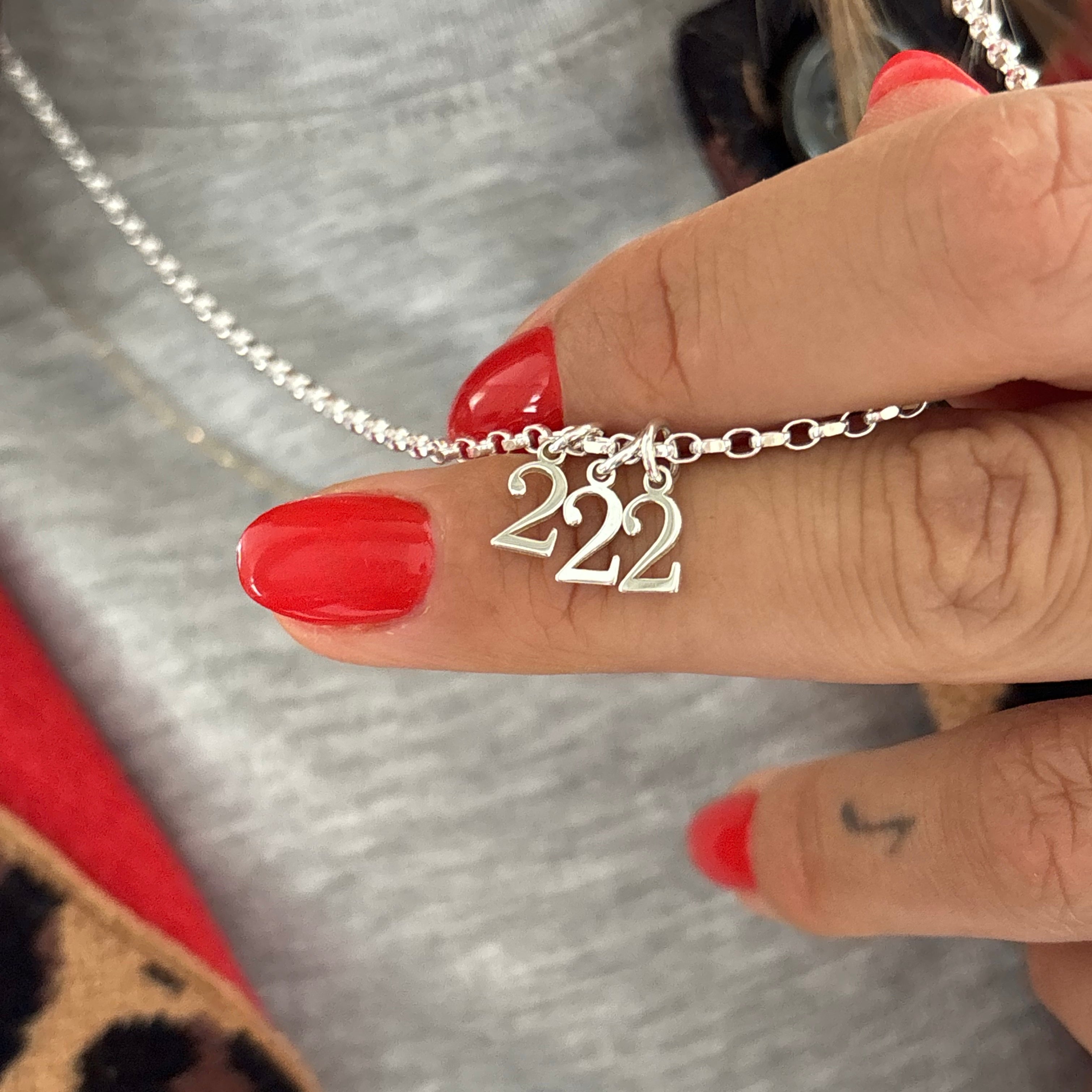 Sterling Silver necklace with '222' pendant held by a hand with red nail polish.