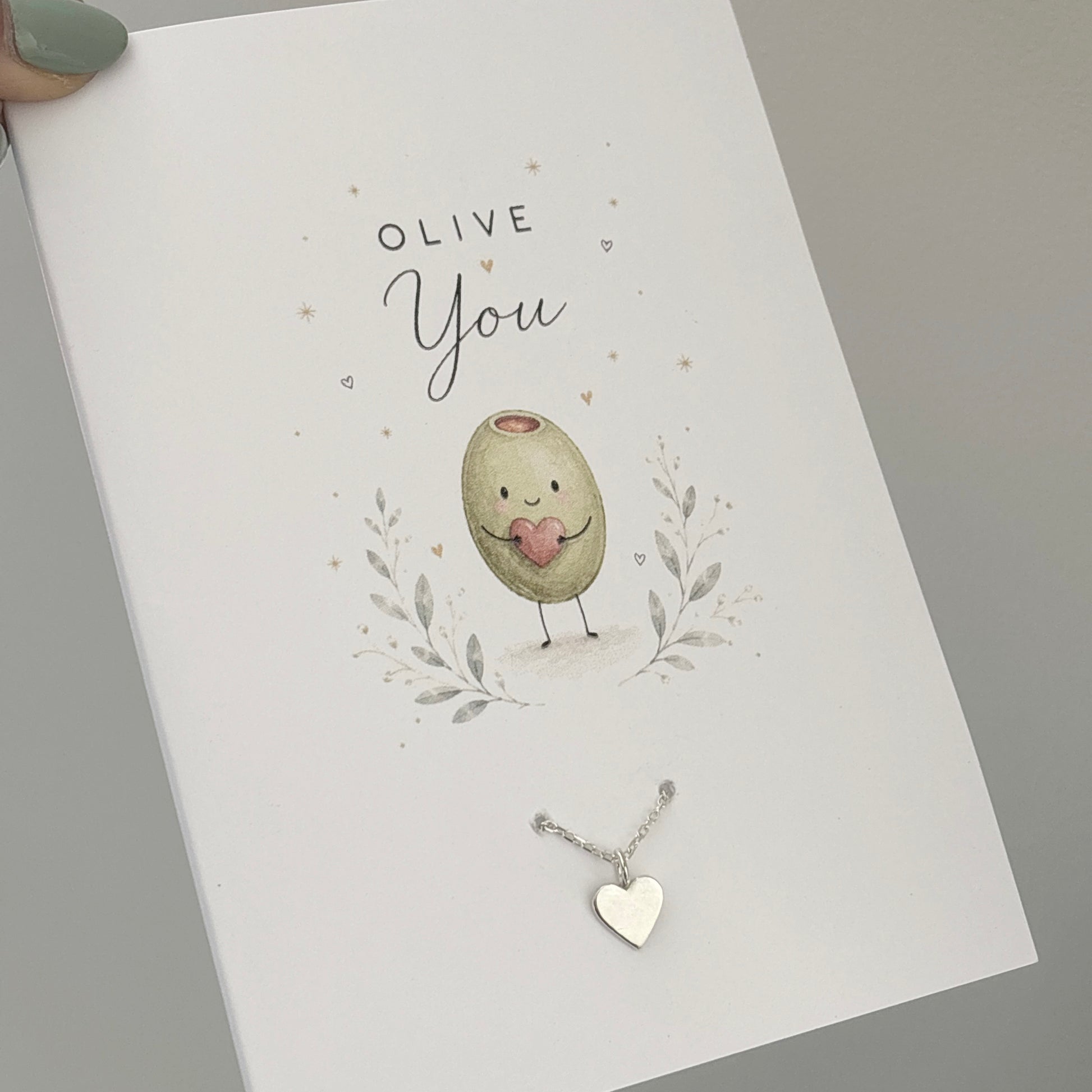 Greetings car with an Olive on the front saying “Olive You” with a sterling silver heart charm bracelet on the front 