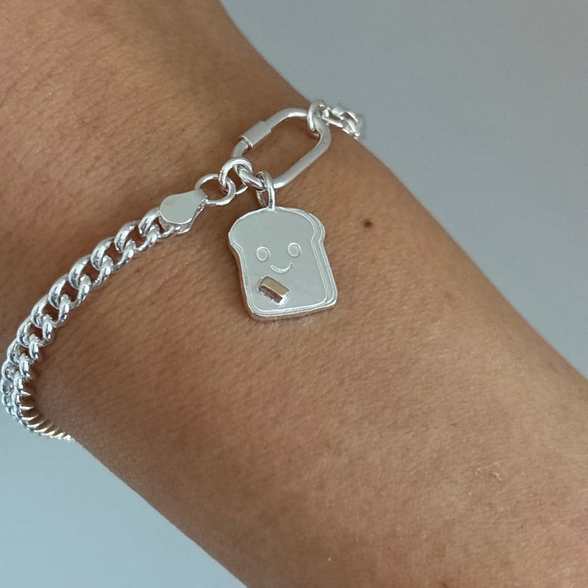 Sterling silver bracelet with Happy Toast charm and 9ct gold butter on wrist.