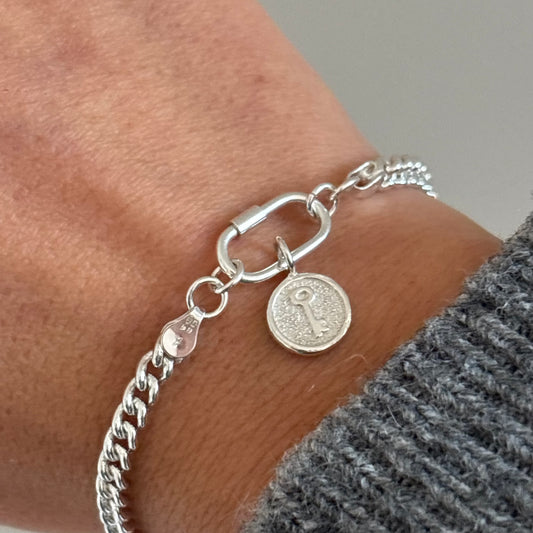 Sterling silver key charm bracelet on curb chain with carabiner clasp, worn on wrist – handmade by Theodore & Olive Jewellery