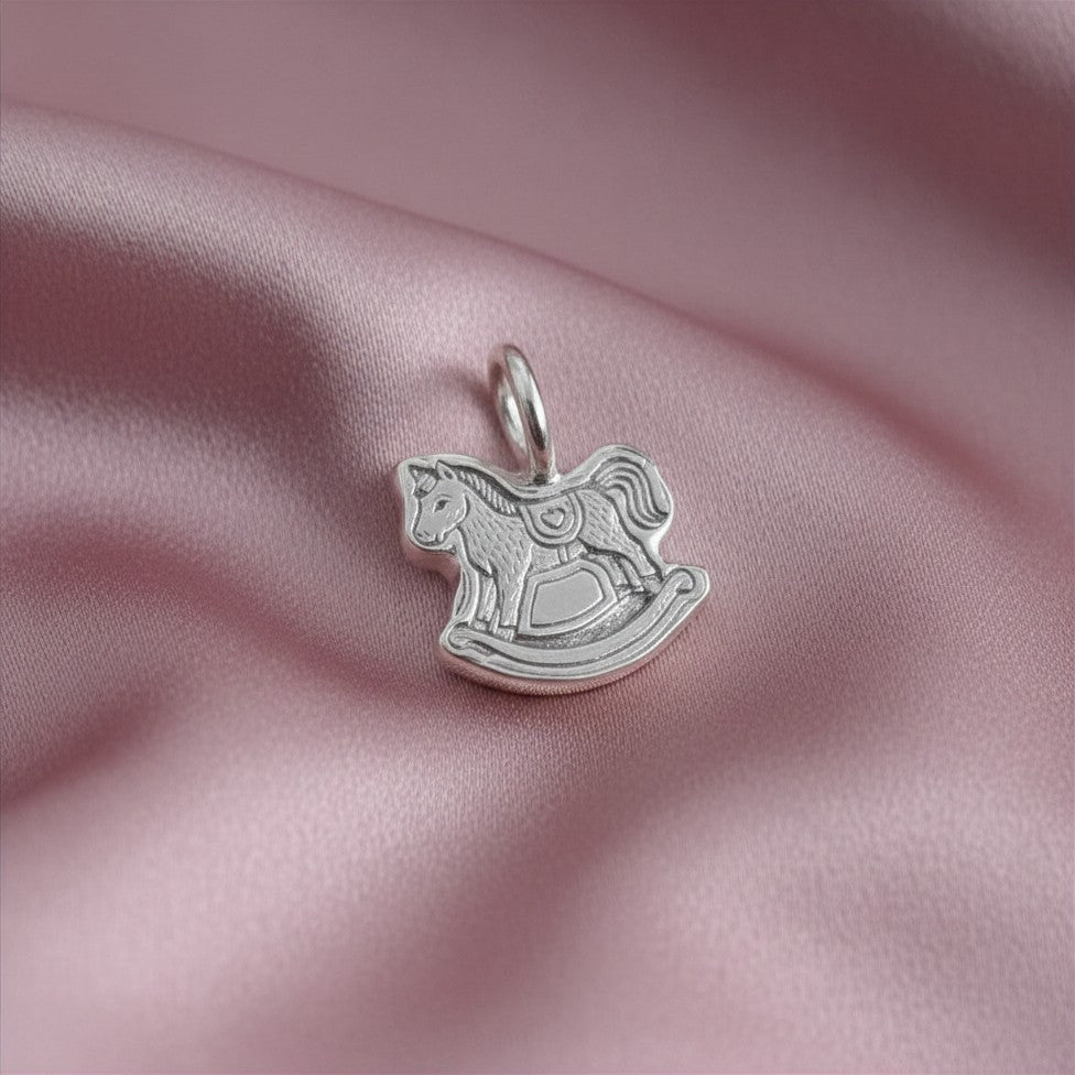 Silver rocking horse pendant on a pink satin background