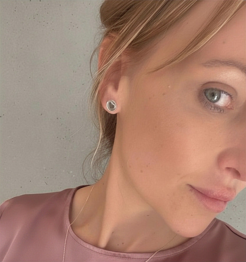 Close-up of a woman wearing heart-shaped earrings with a neutral background