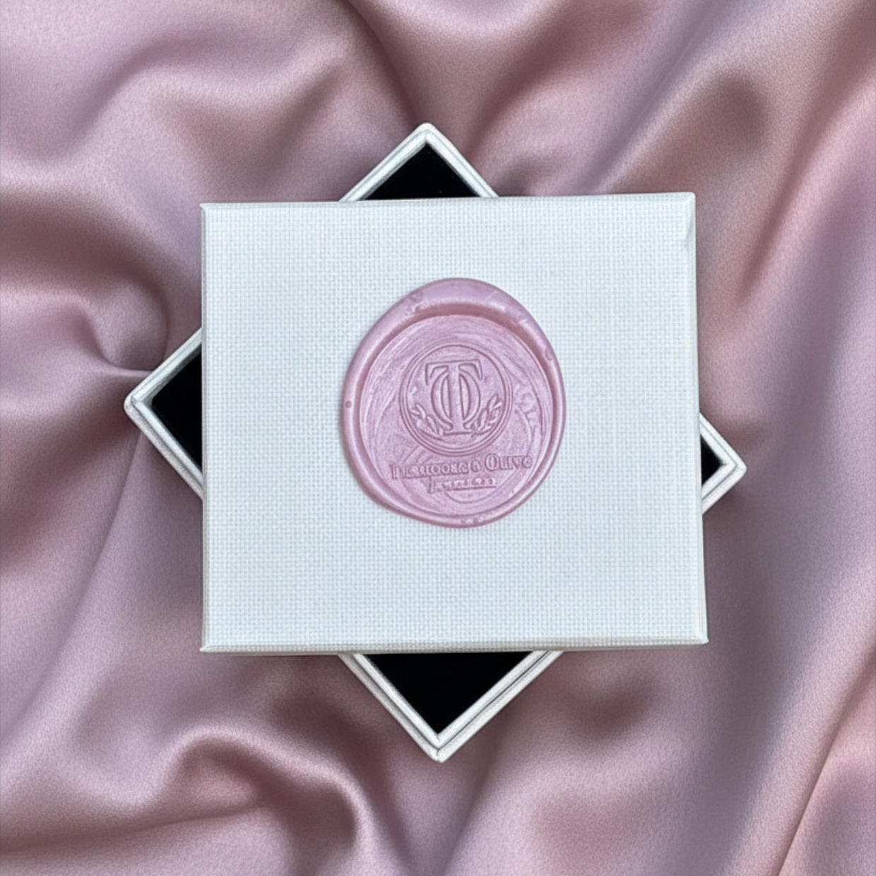 White box with a pink seal on a pink satin background
