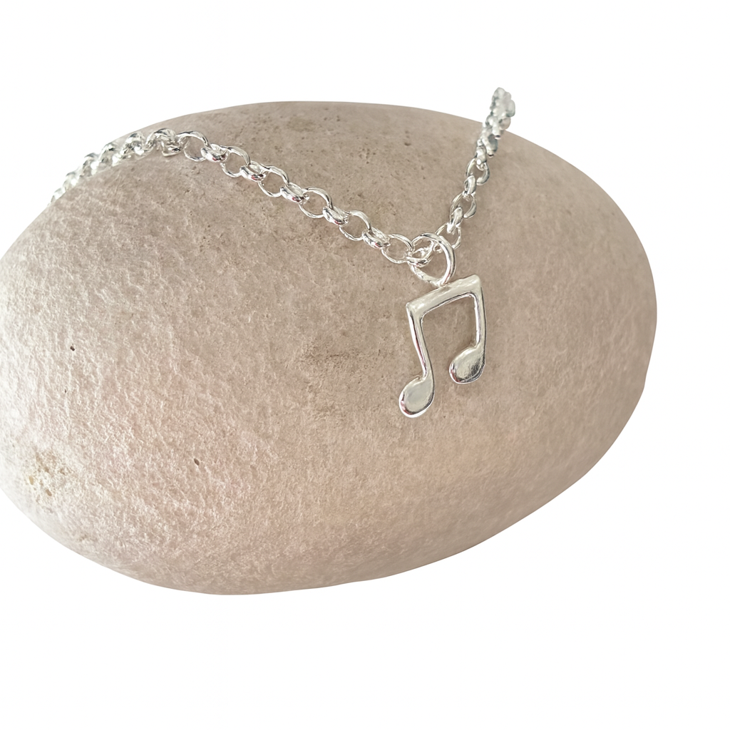 A silver belcher chain necklace with a music note charm 