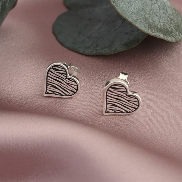 Silver zebra print heart studs laid on dusky link satin