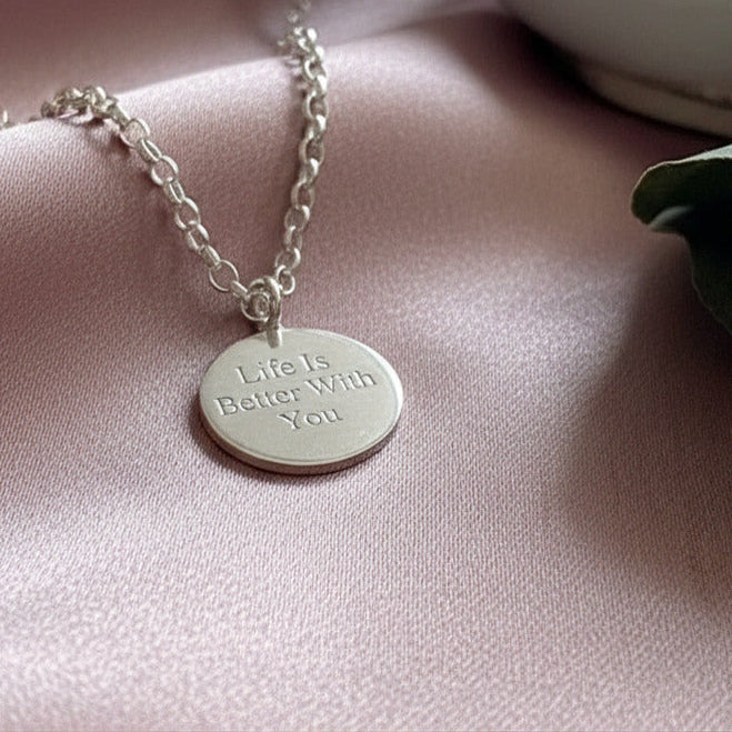Silver necklace with a pendant on a pink surface
