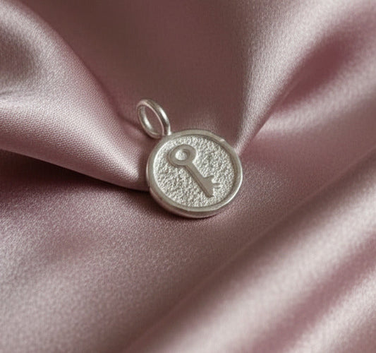Silver key pendant on pink satin fabric