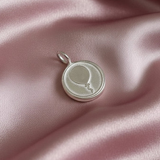 Silver pendant with a balloon design on pink fabric