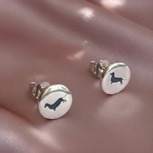 Silver earrings with dachshund design on a pink fabric background