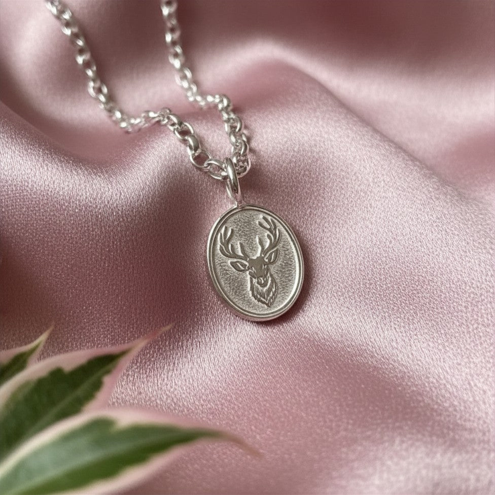 Silver necklace with a deer pendant on a pink satin background