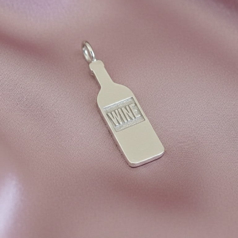 Silver ‘WINE' bottle charm on a pink satin background