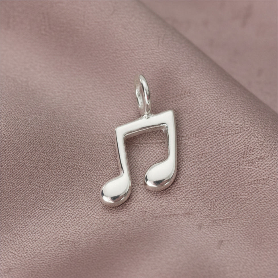 Silver music note pendant on a pink textured surface