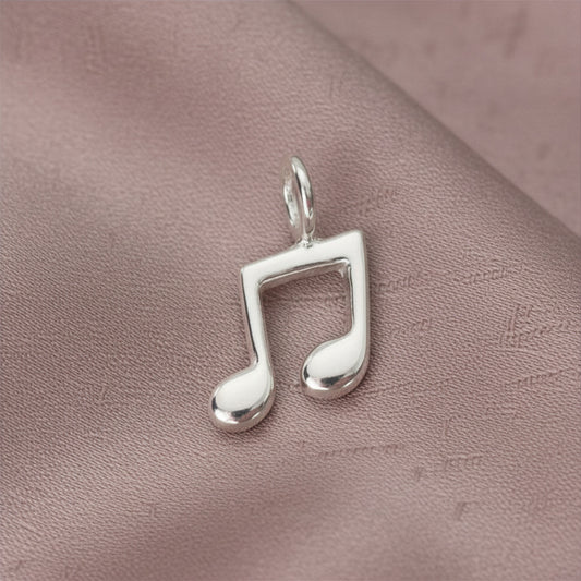 Silver music note pendant on a pink textured surface