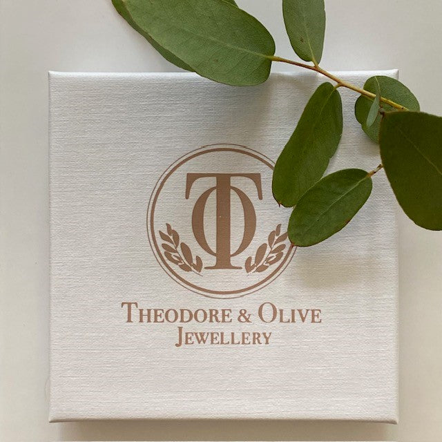 Jewellery box with 'Theodore & Olive Jewellery' logo and green leaves on a light background